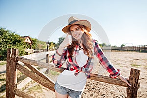 Smiling cheerful redhead cowgirl in hat showing thumbs up gesture