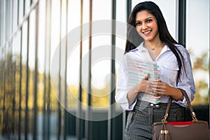 Smiling cheerful warm portrait of a successful young female entrepreneur entering a new business career, carrying organizer, plann