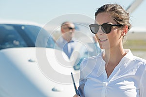 Smiling cheerful woman at airport with light aircraft