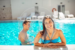 Smiling cheerful woman swimming in a clear pool on a sunny day.Having fun on vacation pool party.Friendly female enjoying relaxing