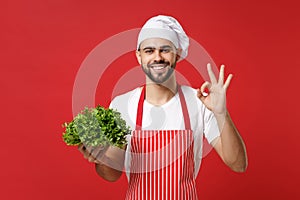 Smiling chef cook or baker man in striped apron white t-shirt toque chefs hat isolated on red background. Cooking food