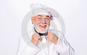 Smiling chef, cook or baker in uniform and chef hat in kitchen restaurant and hotel. Male chef in white hat adjust bow