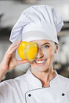 smiling chef covering eye with bell pepper