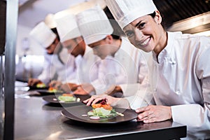 Smiling chef with garnished food plate in the kitchen