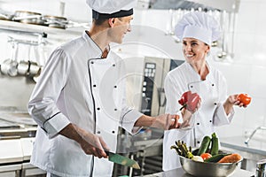 smiling chef giving red bell pepper to colleague