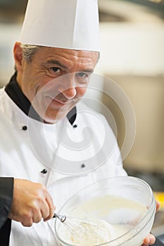 Smiling chef whisking cream