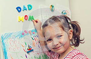Smiling child forms mom dad words on refrigerator