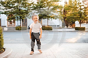 Smiling child girl 4-5 year old wear trendy clothes walking in city street outdoor.