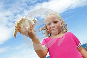 Smiling child girl with big sea shell