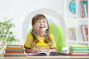Smiling child girl reading book at home