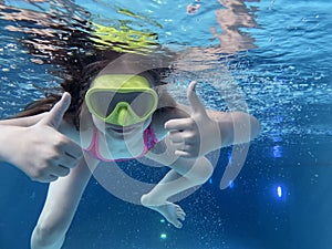 Smiling child in goggles swim, dive in the pool with fun - jump deep down underwater. Healthy lifestyle, people water