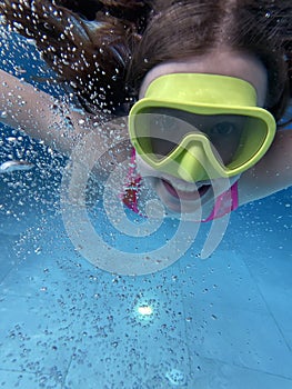 Smiling child in goggles swim, dive in the pool with fun - jump deep down underwater. Healthy lifestyle, people water