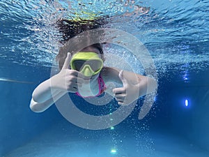 Smiling child in goggles swim, dive in the pool with fun - jump deep down underwater. Healthy lifestyle, people water