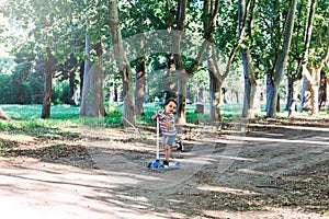 Smiling child on kick scooter in the countryside.