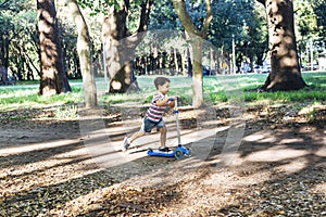 Smiling child on kick scooter in the countryside.