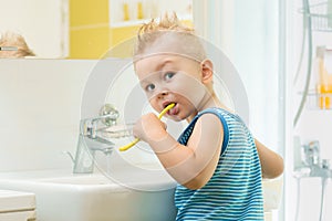 Smiling child kid boy brushing and clean teeth in bathroom himself