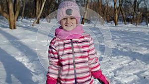 Smiling child kid running, having fun, dancing, fooling around on snowy road in winter park forest