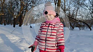 Smiling child kid walking, having fun, relaxing, looking around on snowy road in winter park forest