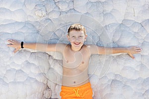 Smiling child leaning against calcium mineral formations in pamukkale