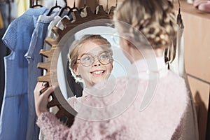 smiling child looking at mirror in her hands at store interior