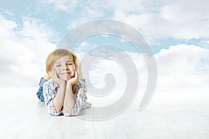 Smiling child lying down, small kid blue sky