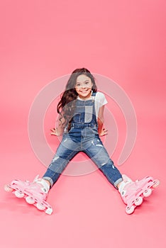 Smiling child in overalls and roller blades looking at camera