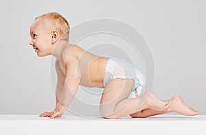 Smiling child. Portrait of little cute toddler boy, baby in diaper crawling isolated over gray studio background