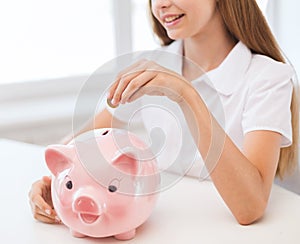 Smiling child putting coin into big piggy bank