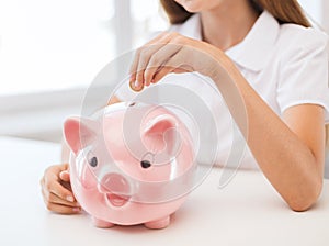 Smiling child putting coin into big piggy bank