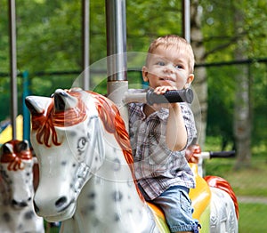 Smiling child riding a toy horse carousel