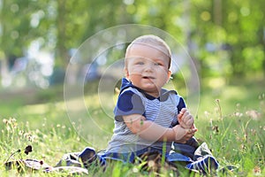 Smiling child seting outdoors in summer park