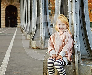 Smiling child sitting on Pont de Bir-Hakeim bridge in Paris