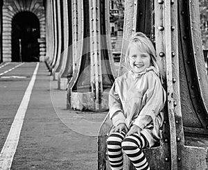 Smiling child sitting on Pont de Bir-Hakeim bridge in Paris