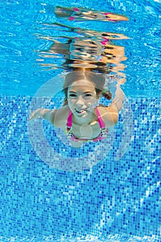 Smiling child swims underwater in pool