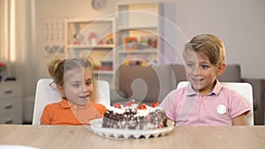 Smiling children looking at chocolate cake on table, childhood happiness, gift