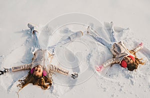 Smiling children lying on snow with copy space. Funny kids making snow angel. Children playing and making a snow angel