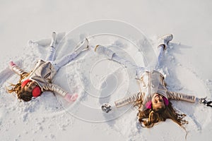 Smiling children lying on snow with copy space. Funny kids making snow angel. Children playing and making a snow angel