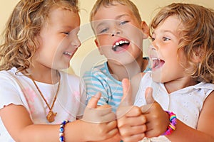 Smiling children three together shows ok gesture