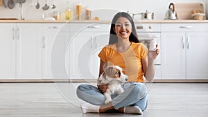 Smiling chinese lady with cute doggy showing pets supplement jar