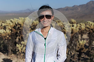 A smiling chinese woman standing in a cholla cactus garden