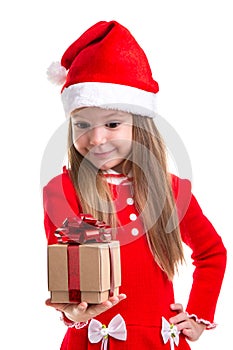 Smiling christmas girl looking at the gift holding it in the hand, wearing a santa hat isolated over a white background