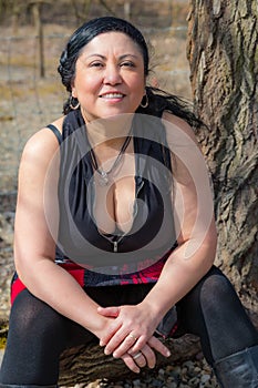 Smiling chubby middle aged Latin American woman sitting and looking at camera