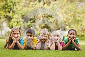 Smiling classmates lying in a row in grass