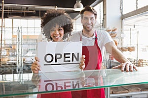 Smiling co-workers showing open sign