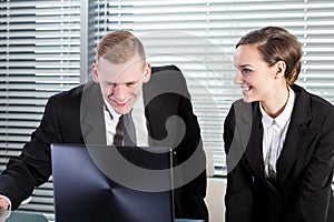 Smiling co-workers using laptop
