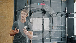 Smiling coach motivating young woman during crossfit training, girl is throwing heavy ball