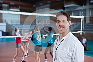 Smiling coach standing in the volleyball court