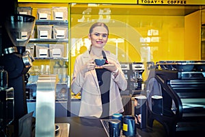 Smiling Coffee shop owner standing behind counter with cup of coffee