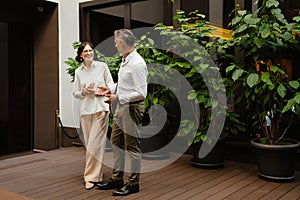 Smiling colleagues discussing business details while standing outdoors