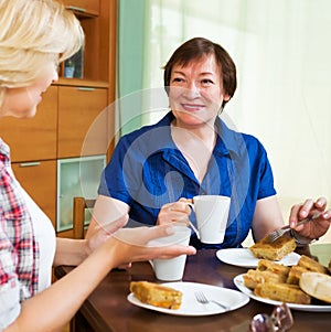 Smiling colleagues drinking tea and talking during coffee break